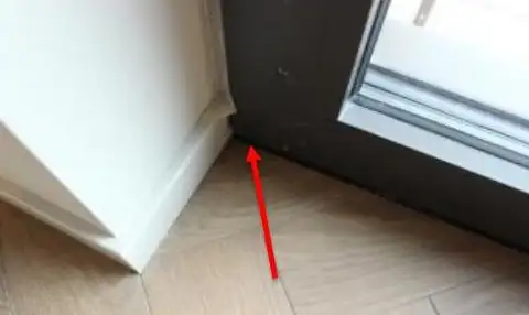 Fuite relevée en pied de mur, à la jonction entre la plinthe, le sol et le dormant d’une porte-fenêtre.